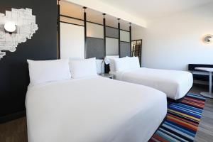 two beds in a hotel room with white sheets at Aloft by Marriott Reno-Tahoe International Airport in Reno +20 photos