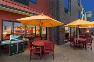 een tafel en stoelen met parasols op een patio bij TownePlace Suites by Marriott Tulsa North/Owasso in Owasso