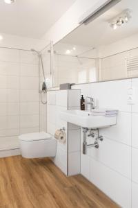 La salle de bains blanche est pourvue d'un lavabo et de toilettes. dans l'établissement Wohnung Bontje, à Juist