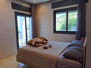 ein Bett in einem Schlafzimmer mit zwei Fenstern in der Unterkunft Ghougine Serenity Residence in Tangier