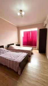 a bedroom with two beds and a window with red curtains at Квартира рядом с морем (3-х комнатная) in Gagra