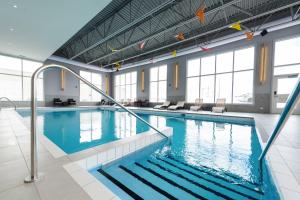 a large swimming pool with blue water in a building at Delta Hotels by Marriott Saguenay Conference Centre in Saguenay
