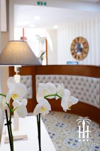 a vase filled with white flowers next to a bed at Hotel Palma in Castellammare di Stabia