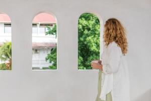 Una mujer con un traje blanco mirando por una ventana en The Neela Boutique Hotel Stone Town, en Zanzíbar