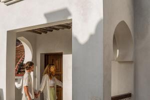 um homem e uma mulher a andar por um corredor em The Neela Boutique Hotel Stone Town em Zanzibar