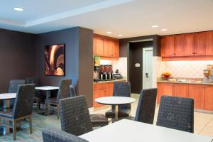 a dining room with tables and chairs and a kitchen at Residence Inn Toledo Maumee in Maumee