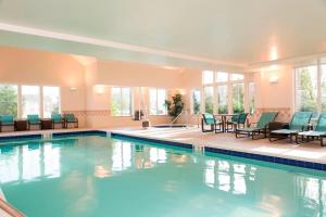uma grande piscina com cadeiras, mesas e janelas em Residence Inn Toledo Maumee em Maumee