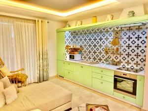 a kitchen with green cabinets and a couch at Beach Garden Paradise in Durrës