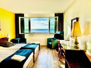 een hotelkamer met een bed, een bureau en een raam bij Hotel de l'Europe in Dieppe