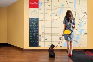 una mujer paseando a un perro delante de un mapa en TownePlace Suites by Marriott Saskatoon, en Saskatoon