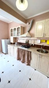 a kitchen with white cabinets and a white tile floor at Квартира рядом с морем (3-х комнатная) in Gagra