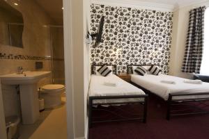 فندق رويال لندن باي سابا في لندن: سريرين في غرفة مع حوض وحمام