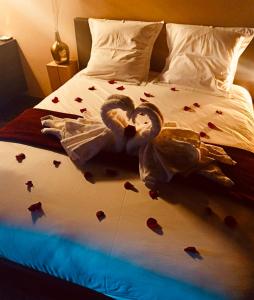 Una cama con pétalos de rosa roja. en Octavie - Suite de luxe à Tournai avec piscine privée, jacuzzi, sauna et hammam en Tournai