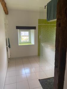 a bathroom with a shower with a window and a tile floor at Gite de la Ville aux Bois in Parigné
