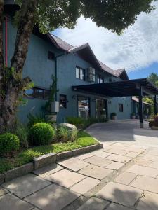 een blauw gebouw met een boom ervoor bij Hotel San Lucas in Gramado