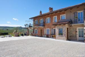 een groot bakstenen huis met een geplaveide oprit bij Agriturismo Cascina Sciulun in Monforte dʼAlba