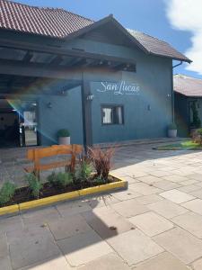 um edifício azul com um banco à frente em Hotel San Lucas em Gramado