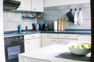 una cocina con armarios blancos y un bol de fruta en una mesa en Nespresso Netflix Work Appartment - 24h Check-In, en Bielefeld