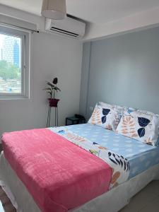 a bedroom with a bed with a pink blanket and a window at Cebu Mini Hotel in Cebu City