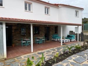 a white house with a patio with a table and chairs at Apartamentos turísticos Praia de Seselle, terraza y jardín a un paso de la playa in Ares