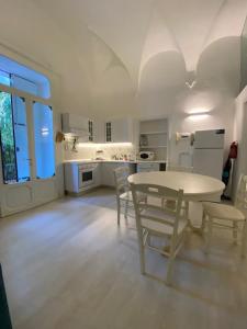 una cucina bianca con tavolo e sedie di DUOMO26 BOUTIQUE APARTMENT a Desenzano del Garda