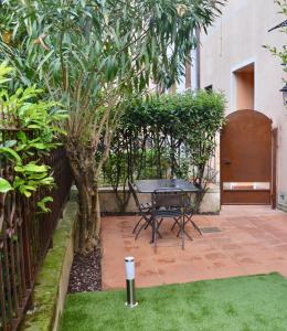a patio with a table and a tree in a yard at DUOMO26 BOUTIQUE APARTMENT in Desenzano del Garda