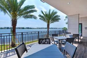 un patio con mesas, sillas y palmeras en Residence Inn by Marriott Fort Walton Beach, en Fort Walton Beach