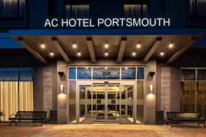 AC Hotel by Marriott Portsmouth Downtown/Waterfront في بورتسموث: مدخل إلى مبنى فندق بورتسموث مع كرسيين