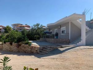 a white house with a stone wall and stairs at Nardi Guesthouse in Ksamil