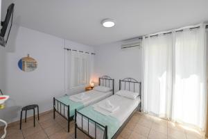 a white room with two beds and a window at Hermes Rooms in Tinos
