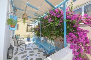 a blue balcony with purple flowers and plants at Hermes Rooms in Tinos