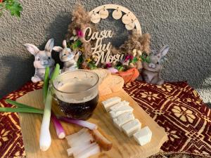 a wooden cutting board with a glass of beer and cheese at CASA LUI MOȘU in Alba Iulia