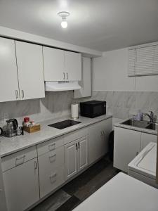 a kitchen with white cabinets and a sink and a microwave at River Park South - 2 Bedroom Basement Suite in Winnipeg