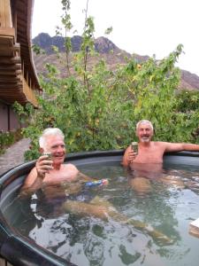 dos hombres mayores en un jacuzzi con sus celulares en Casa de Oren, en Písac