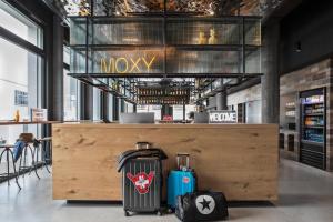 eine Lobby mit zwei Koffern neben einer Theke in der Unterkunft Moxy Rapperswil in Rapperswil-Jona