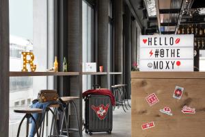 a room with a bar with a suitcase and stools at Moxy Rapperswil in Rapperswil-Jona