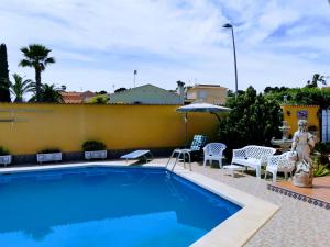 a swimming pool with chairs and a table and an umbrella at Villa SIA in Torrevieja