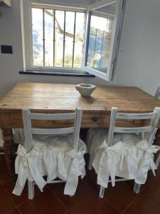 een houten tafel met twee stoelen en een kom bovenop bij Ca' Bianca in San Bartolomeo