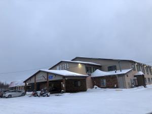 a building covered in snow with cars parked in a parking lot at Luck Country Inn in Luck