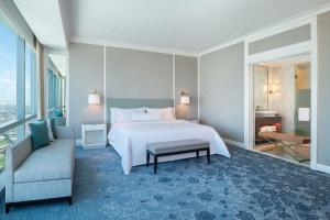 a bedroom with a bed and a couch and a window at The Westin Surabaya in Surabaya