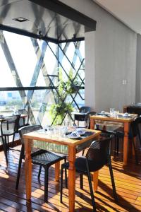 a restaurant with wooden tables and chairs and a large window at Hotel Black Inn Flamboyant in Goiânia