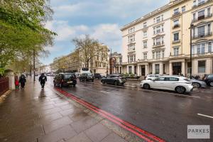a person walking down a street with cars parked at The Cromwell Residences in London