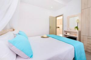 a white bed with blue pillows in a bedroom at Luxury Vacation Villa Irene with private juccuzi in Fira