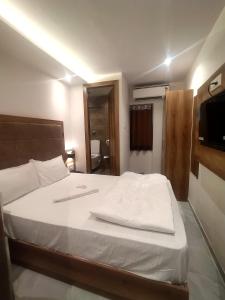 a bedroom with a bed with white sheets and a television at Hotel Kishan Lodging & Boarding in Mumbai