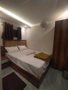 a small bedroom with a bed with white sheets at Hotel Kishan Lodging & Boarding in Mumbai