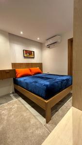 a bedroom with a bed with blue sheets and an orange pillow at شاليه Aqua بورتو جولف مارينا in El Alamein