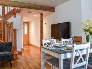 a dining room with a table and chairs and a television at Pinewood Cottage in Marhamchurch