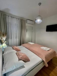 ein Schlafzimmer mit einem großen Bett mit rosa und weißen Kissen in der Unterkunft Apartment Seaside Orebić in Orebić