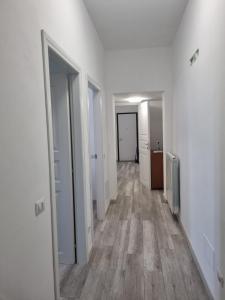pusty korytarz z białymi ścianami i drewnianą podłogą w obiekcie Appartamento viktor w mieście Cislago