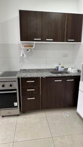 Una cocina con gabinetes de madera y encimera. en Depto Magallanes, en Ushuaia